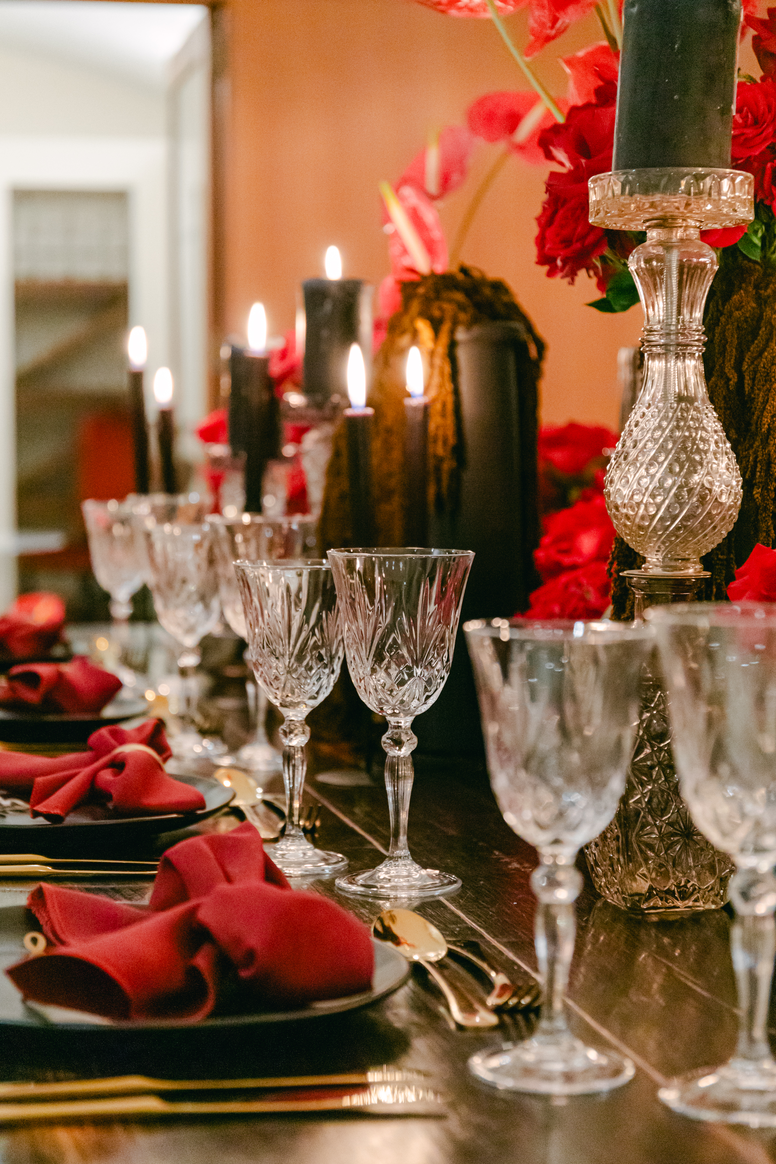 Crystal glassware and red roses on a candlelit table