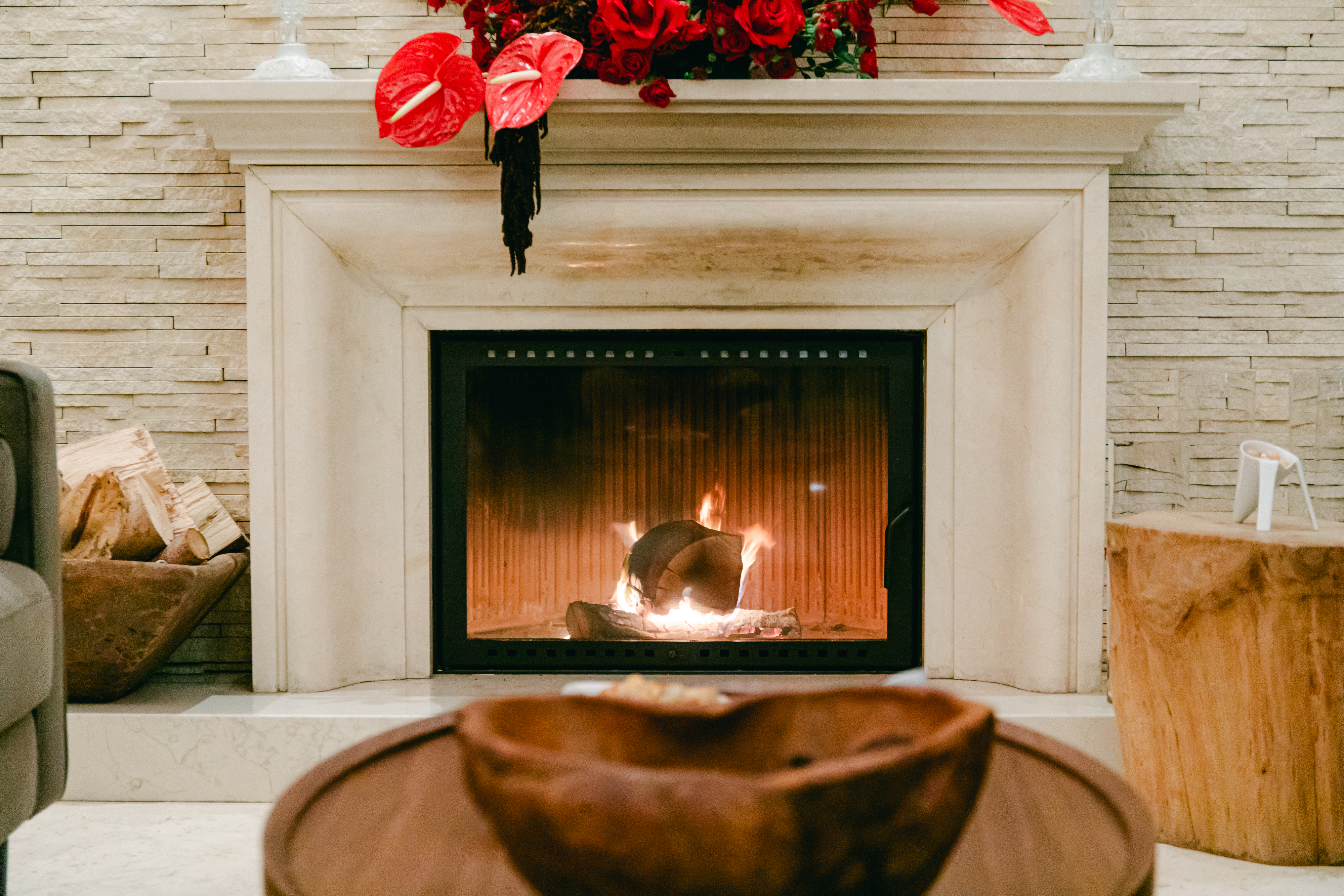 Lit fireplace dressed with red anthuriums and roses