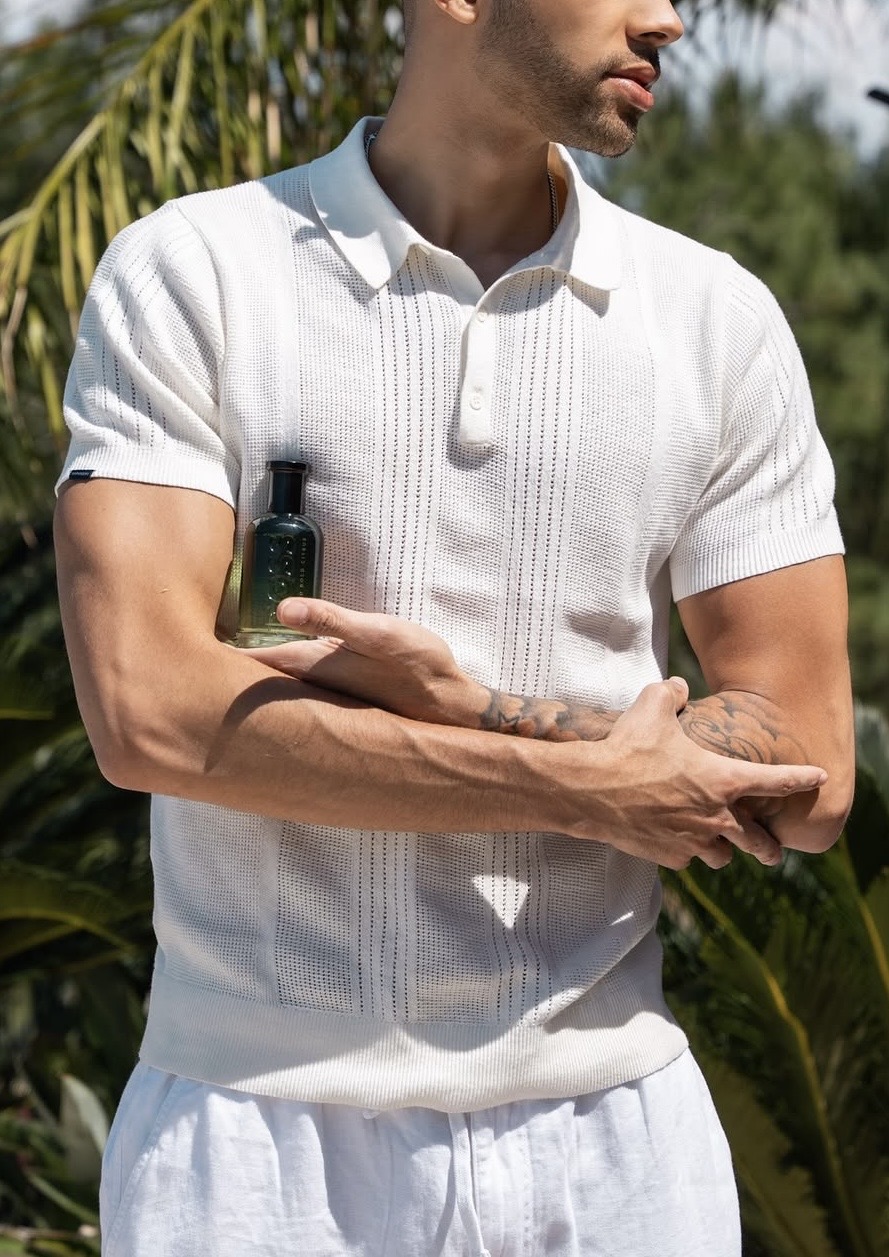 Model in a white knitted polo among the palms